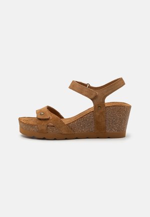 Braune Wildleder-Wedgesandalen mit einem verstellbaren Knöchelriemen, strukturiertem Kork-Plateau und kontrastierender Außensohle. Mit einem dekorativen Knopfdetail.
