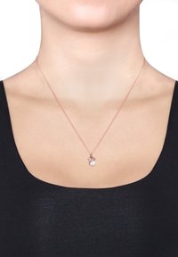 Rose gold kæde halskæde med en perlevedhæng og blomster charm. Kæden er delikat med en glat finish og subtil tekstur.