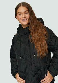 Schwarze Steppjacke mit hohem Kragen und Kapuze. Verfügt über Reißverschlusstaschen und verstellbare Kordelzüge. Strukturierter, gestepptes Material. Lange Ärmel.