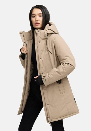 Beige pufferjas met een capuchon, voorzien van een rits- en drukknoopsluiting, zijzakken en een gestructureerde afwerking, gedragen over een zwarte top.