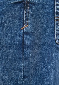 Blue denim jeans featuring orange stitching, a smooth texture, and a close-up view of the fabric and seam details.