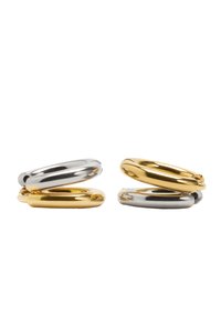 Złote i srebrne połączone pierścienie o gładkich, zaokrąglonych krawędziach; błyszczące metaliczne wykończenie; dwa złote pierścienie i dwa srebrne pierścienie ustawione razem.