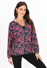 Letvægts marineblå jakke med et blomster- og leopardprintdesign i røde og rosa nuancer. Inkluderer lynlås og hætte samt elastiske manchetter.