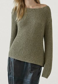 Pull en maille côtelée vert olive avec un col décolleté épaule, des manches longues et une coupe décontractée, assorti à une jupe en cuir noire.
