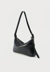 Fekete, texturált bőr válltáska ezüst színű cipzárral és állítható, csatos pánttal, világos egyszínű háttér előtt bemutatva.