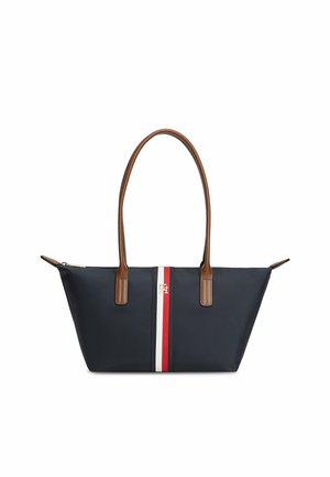 Marineblå shopper taske med brune håndtag og centralt rødt, hvidt og marineblåt stribemønster med lille guldlogo foran.