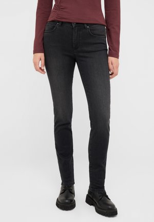 Černé denimové džíny slim fit, které mají pět kapes, poutka na opasek a jemné vyblednutí. Nosené s černými šněrovacími botami.