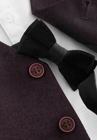 Tessuto viola testurizzato con una cravatta nera, camicia bianca e bottoni bordeaux. Presenta eleganti motivi e colori a contrasto.