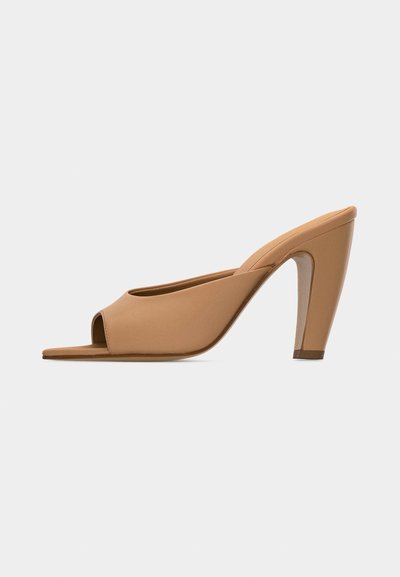 Mule beige à bout ouvert et talon haut, finition lisse et talon effilé, sur un fond clair uni.