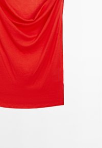 Rode top van lichtgewicht stof, met een zachte textuur en een iets losse pasvorm. Geen zichtbare patronen of hardwaredetails.