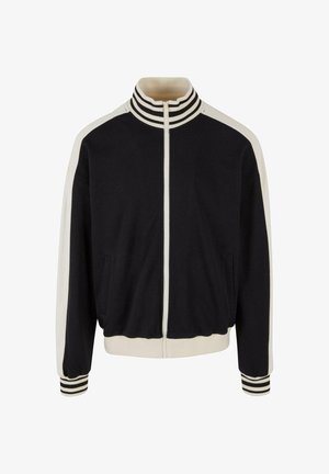 Czarna kurtka zapinana na zamek z kremowymi paskami na ramionach i mankietach. Posiada boczne kieszenie oraz prążkowany kołnierz. Wykonana z miękkiego materiału.