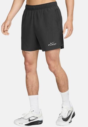 Pantaloni corti da uomo neri in cotone tecnico con elastico in vita, dotati di tasche laterali e logo Nike riflettente sul lato sinistro. Il materiale sembra leggero.