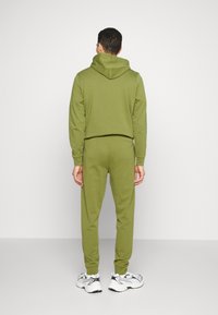 Olivgrön hoodie och matchande sweatpants i mjukt material. Hoodien har dragsko och joggers har en figurnära design.