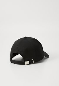 Svart baseballcap med buet skjerm, justerbar stropp bak, med en metallisk tag som har "EAZ" logo og teksturert stoff.