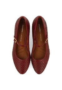 Bailarinas de cuero trenzado rojo con puntera redonda, detalle de hebilla dorada y forro interior liso marrón. La superficie texturizada añade interés visual.