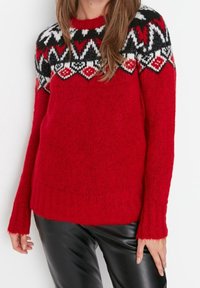 Rode gebreide trui met een gebreide yoke in zwart, wit en rood. Beschikt over lange mouwen, ribgebreide manchetten en een zachte textuur.