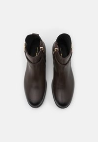 Bottines marron en cuir lisse, dotées d'un bout arrondi et de zips dorés sur les côtés, avec une doublure intérieure texturée.