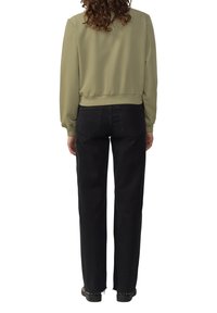 Khaki skrócony sweatshirt z prążkowanym wykończeniem i dopasowanymi rękawami, w połączeniu z czarnymi spodniami o szerokich nogawkach z surowym dołem i tylnymi kieszeniami.