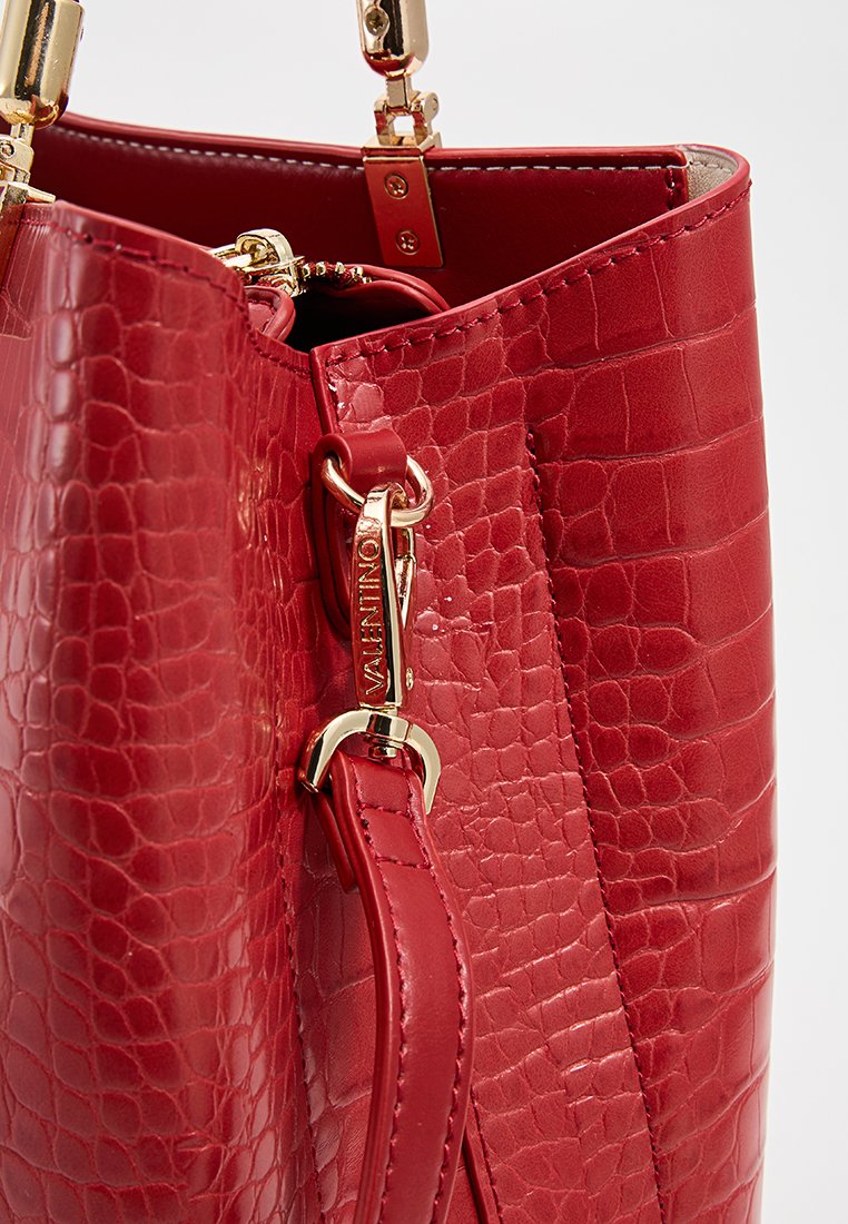 Borsa a tote in pelle rossa con motivo coccodrillo e hardware dorato, dotata di cinture staccabili e cuciture dettagliate lungo i bordi.