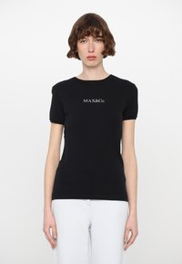 Mustassa lyhyessä hihassa t-paidassa on puuvillaa, pyöreä pääntie ja valkoinen brodeerattu "MAX&Co." -logo rinnassa.