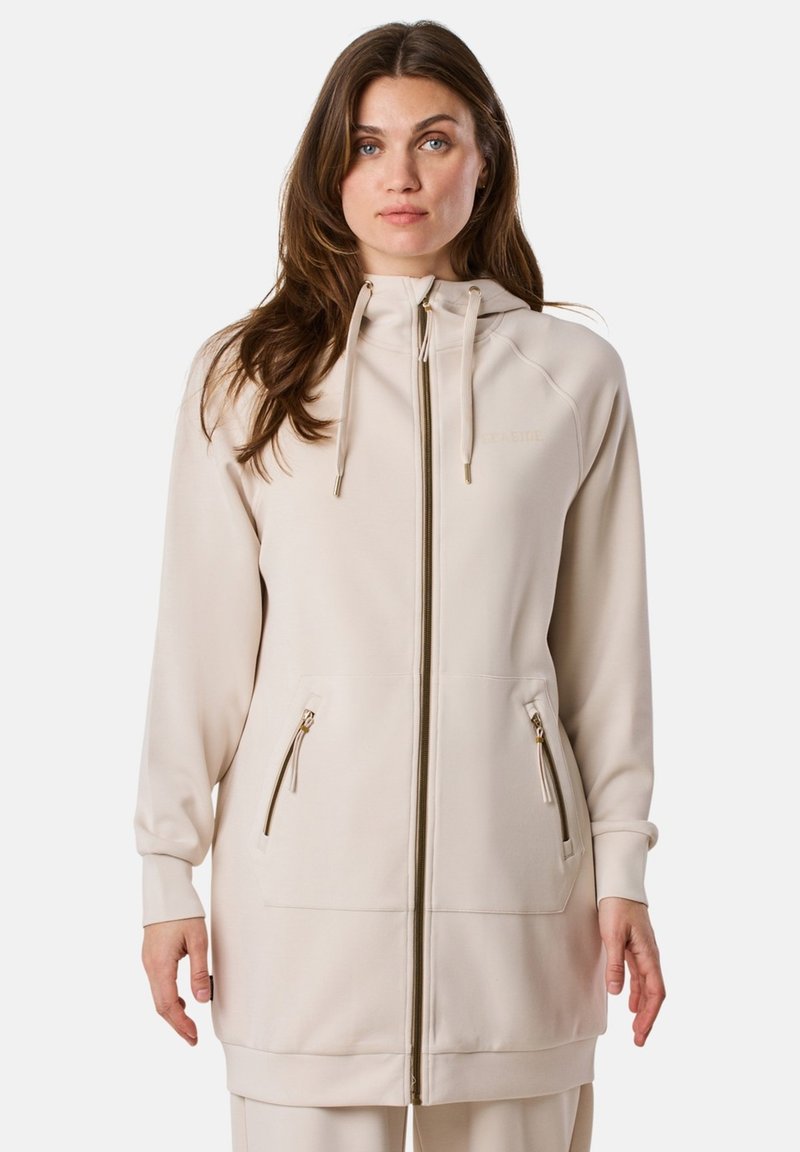 Beige zip-up hoodie met trekkoord, twee geperforeerde zijzakken, rib gebreide manchetten en een rechte silhouet. Zachte stof met een gladde textuur.