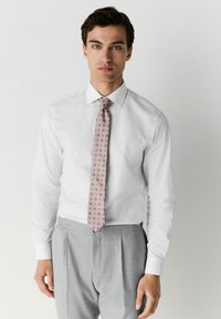 Weißes Hemd mit spitzem Kragen, hellrosa gemusterte Krawatte und hellgraue gefaltete Hose. Glattes Material, taillierte Passform.
