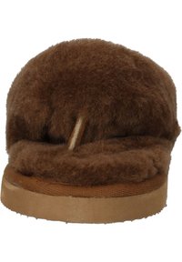 Hnědé ovčí kožené pantofle s měkkým, chlupatým vrškem, zaobleným tvarem a podrážkou připomínající semiš. Má minimalistický design a jednoduché švy.