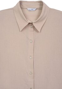 Chemise rose pâle boutonnée avec un tissu texturé, un col, et cinq boutons sur le devant. L'étiquette indique "CALLIOPE" avec la taille "S".
