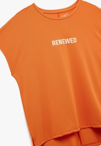 Oranje T-shirt met korte mouwen, een ronde halslijn en het woord "RENEWED" in het wit. Zacht, rekbaar materiaal met een relaxte pasvorm.