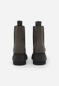 Dark green leather ankle boots with black elastic panels, rubber soles, and contrasting stitching. Features pull tabs for easy wear.