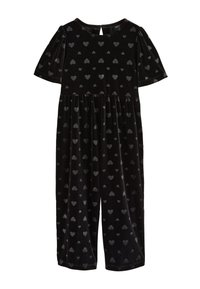 Tuta corta in velluto nero con maniche corte e scollo rotondo, decorata con piccoli motivi a cuore lucidi su tutta la superficie.