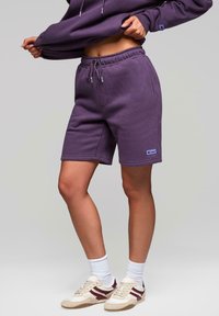 Fialové bavlněné šortky s elastickým pasem a stahovací šňůrkou. Mají boční kapsy a malé logo značky na levém stehně.