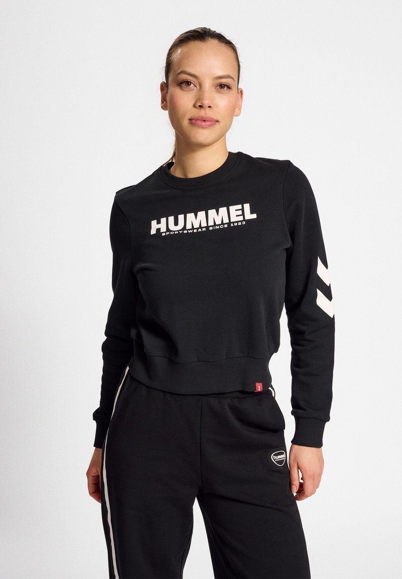 Czarna bluza z bawełnianej mieszanki, z białym logo "HUMMEL", ribbowanym okrągłym dekoltem i akcentami w kształcie chevronu na rękawach.