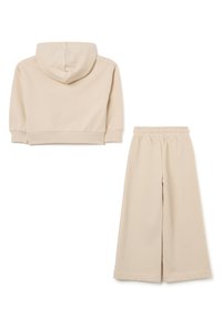 Beige Baumwoll-Hoodie mit Kordelzugkapuze und gerippten Bündchen, kombiniert mit passenden weiten Hosen mit elastischem Bund.