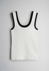 Débardeur en maille blanc sans manches avec une bordure noire autour de l'encolure et des emmanchures, posé à plat sur un fond gris clair.