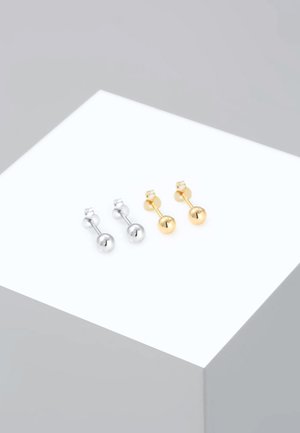 Silberne und goldene Ohrstecker mit einem glatten, sphärischen Design, auf einer weißen Präsentation platziert, die den metallischen Glanz und die klaren Linien zur Schau stellt.