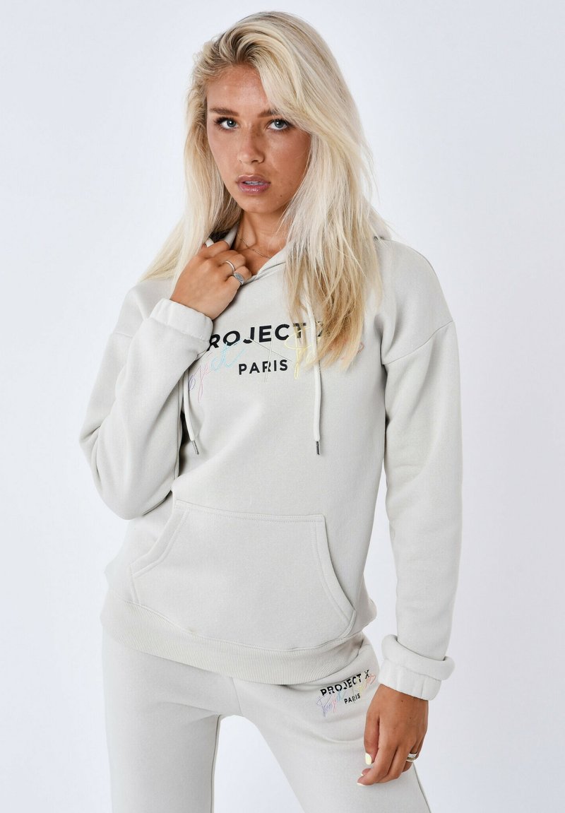 Lichtgrijze hoodie met trekkoorden, een zak aan de voorkant en geborduurde "PROJECT PARIS" tekst in kleurrijke letters. Zachte stoftextuur.