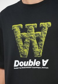 Črna majica s kratkimi rokavi, ki ima puhasto rumeno "W" logo in belo "Double A" besedilo. Narejena iz bombaža s krožnim izrezom.