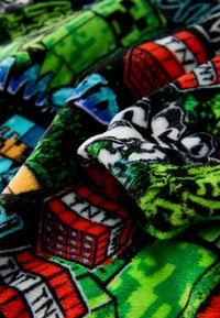 Fleece blanket featuring a vibrant, multicolored pattern with green, black, and red elements, depicting various gaming-themed designs and textures.