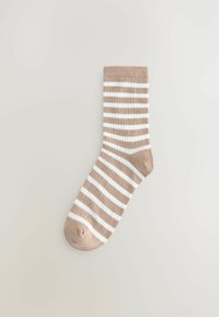 Beige en witte horizontaal gestreepte enkel sok die plat ligt op een lichte neutrale achtergrond.
