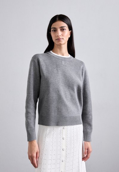 Pull en tricot gris avec un col rond et un ourlet côtelé, présentant des coutures détaillées au niveau de l'encolure et des manches longues.