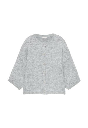 Donna in piedi su una strada lastricata che indossa un cardigan grigio, jeans a gamba larga azzurri e sandali con zeppa neri.