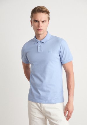 Polo bleu clair en coton doux, doté d'un col classique, d'une patte de boutonnage à deux boutons et d'un patch logo discret sur la poitrine gauche.