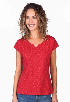 Red short-sleeve top with a keyhole neckline, featuring a small cherry pattern and soft texture, paired with blue denim jeans.