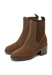 Botas de tobillo de ante marrón con lados elásticos acanalados, tacones bajos y bucles en la parte trasera para ponerlas fácilmente.