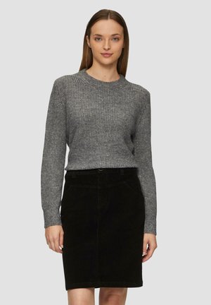 Pull en maille gris avec texture côtelée, associé à une jupe en velours côtelé noire longueur genou avec poches avant et passants de ceinture.