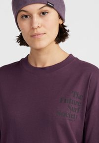 Fialová bavlněná košile s dlouhým rukávem a round neck, na levé straně hrudi s černým textem "Surfová společnost budoucnosti".