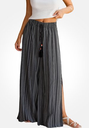 Pantalones de pierna ancha con estampado en blanco y negro, cintura con cordón ajustable, aberturas laterales y detalles de borlas. Tejido suave y fluido.