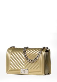 Sac à main matelassé en or métallique avec un motif en chevrons, une chaîne en argent et un matériel rectangulaire en argent présentant un logo en relief.