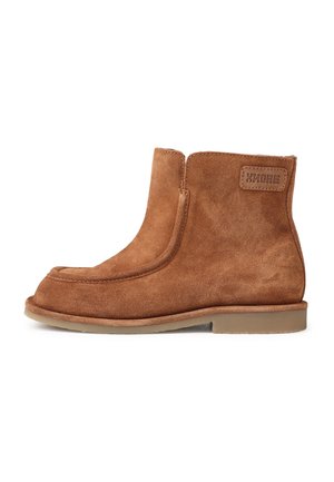 Bottines en daim marron avec un bout arrondi et des coutures latérales. Elles présentent un patch logo discret et une semelle en caoutchouc plate.